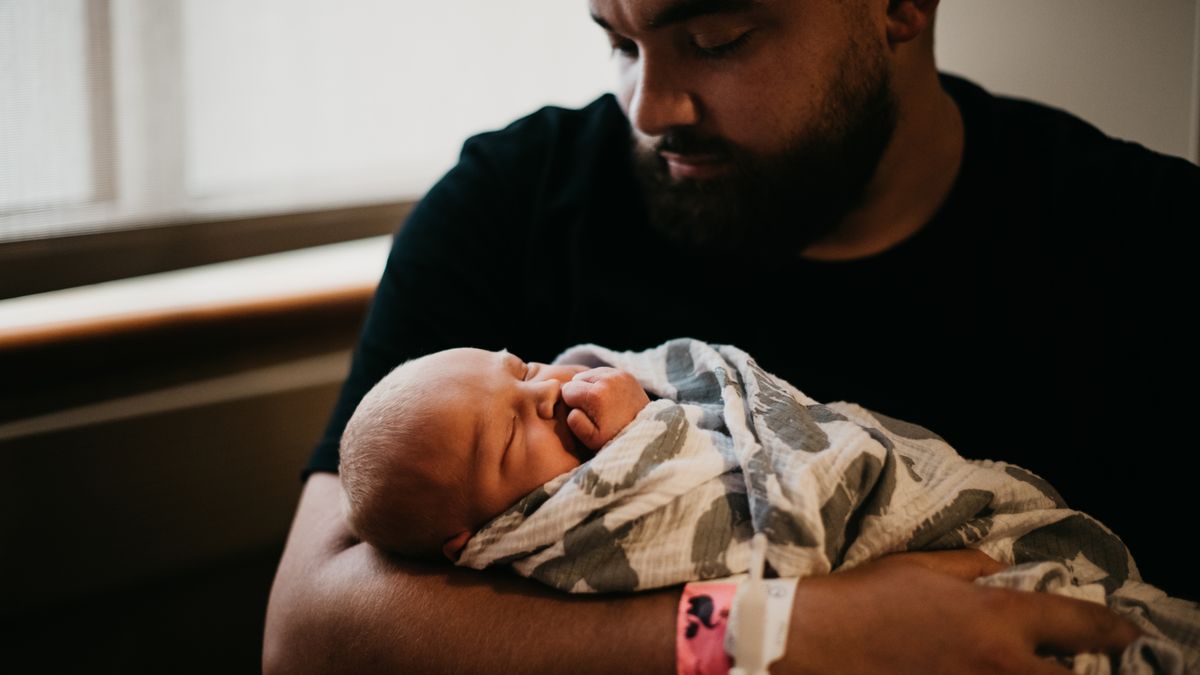 Military parents holding their newborn in a hospital room