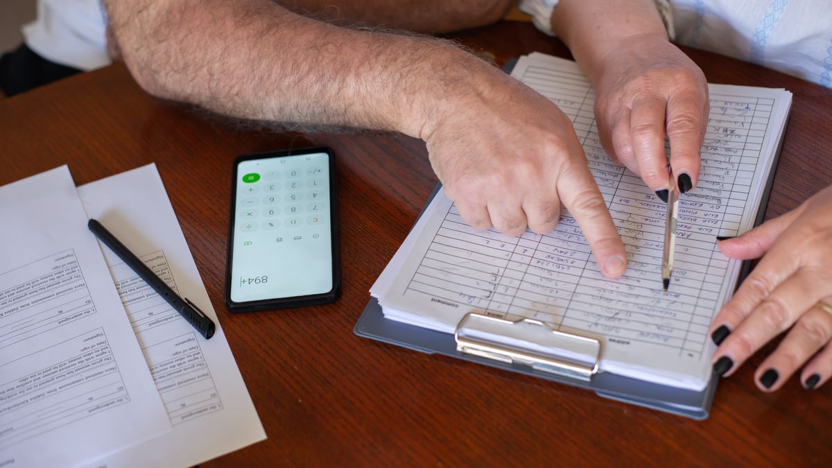 retiring service member and spouse reviewing financial forms at a kitchen table