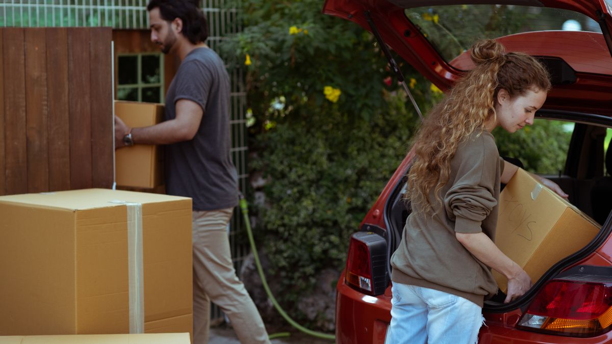 Military family loading labeled moving boxes into a rental truck