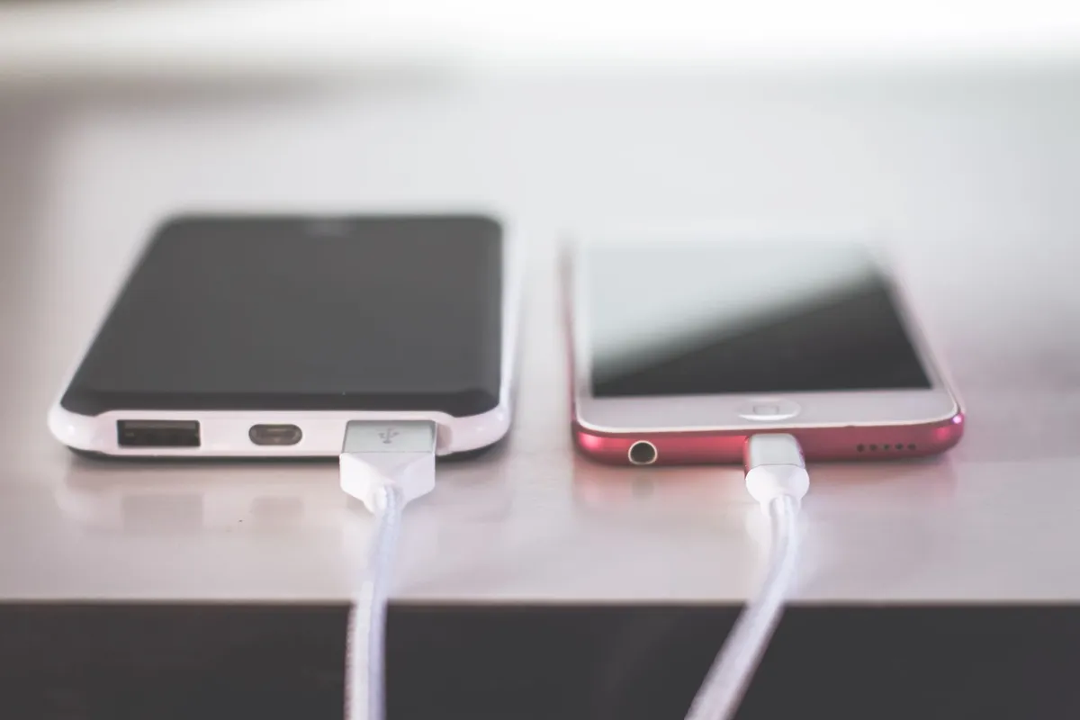 An older smartphone plugged into a wall charger on a kitchen counter