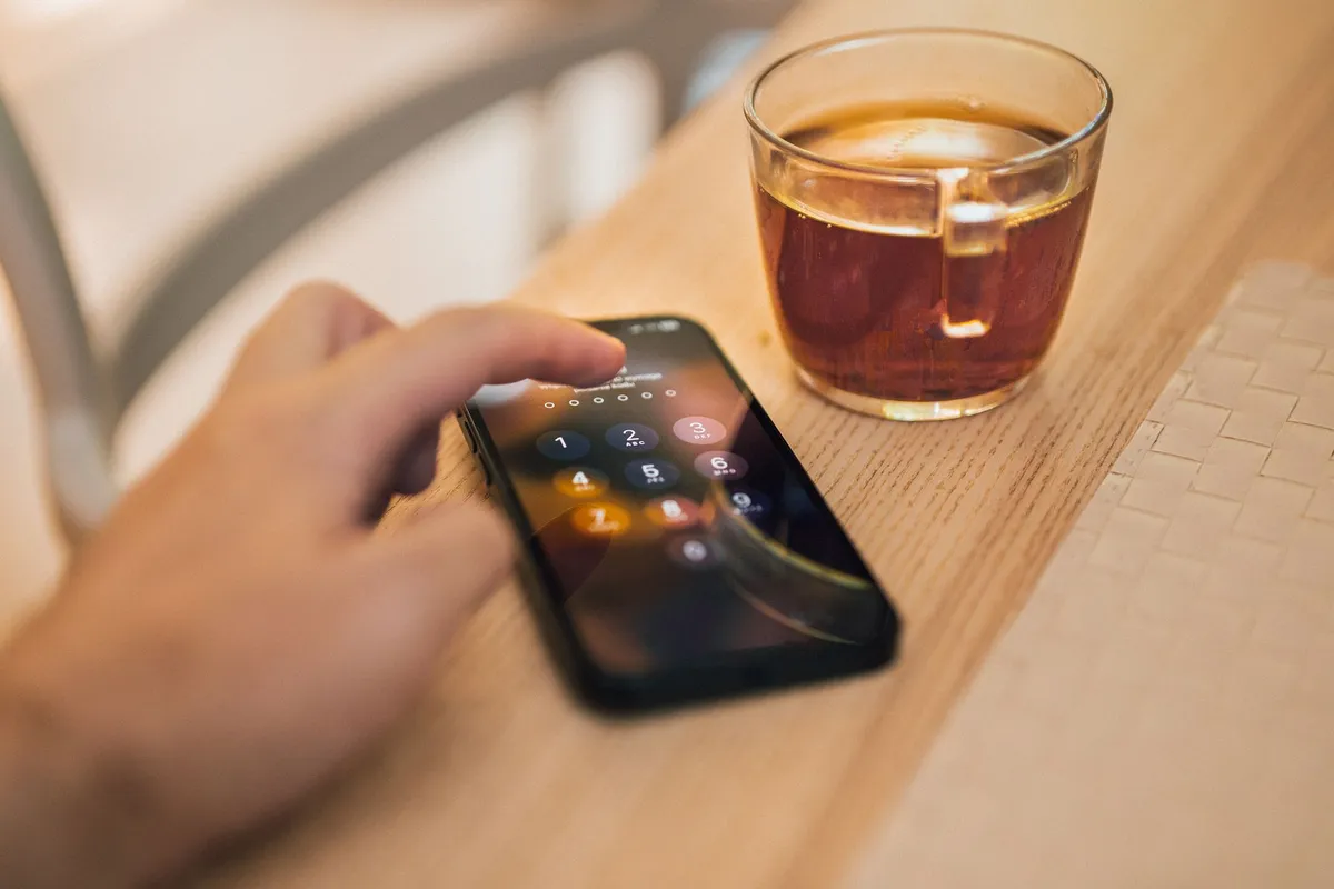 A hand holding a smartphone showing a lock screen with emergency information