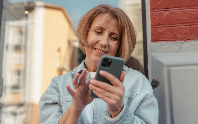 A Lifeline-eligible user checking a smartphone while wondering Who has iPhones for free? through government-supported programs