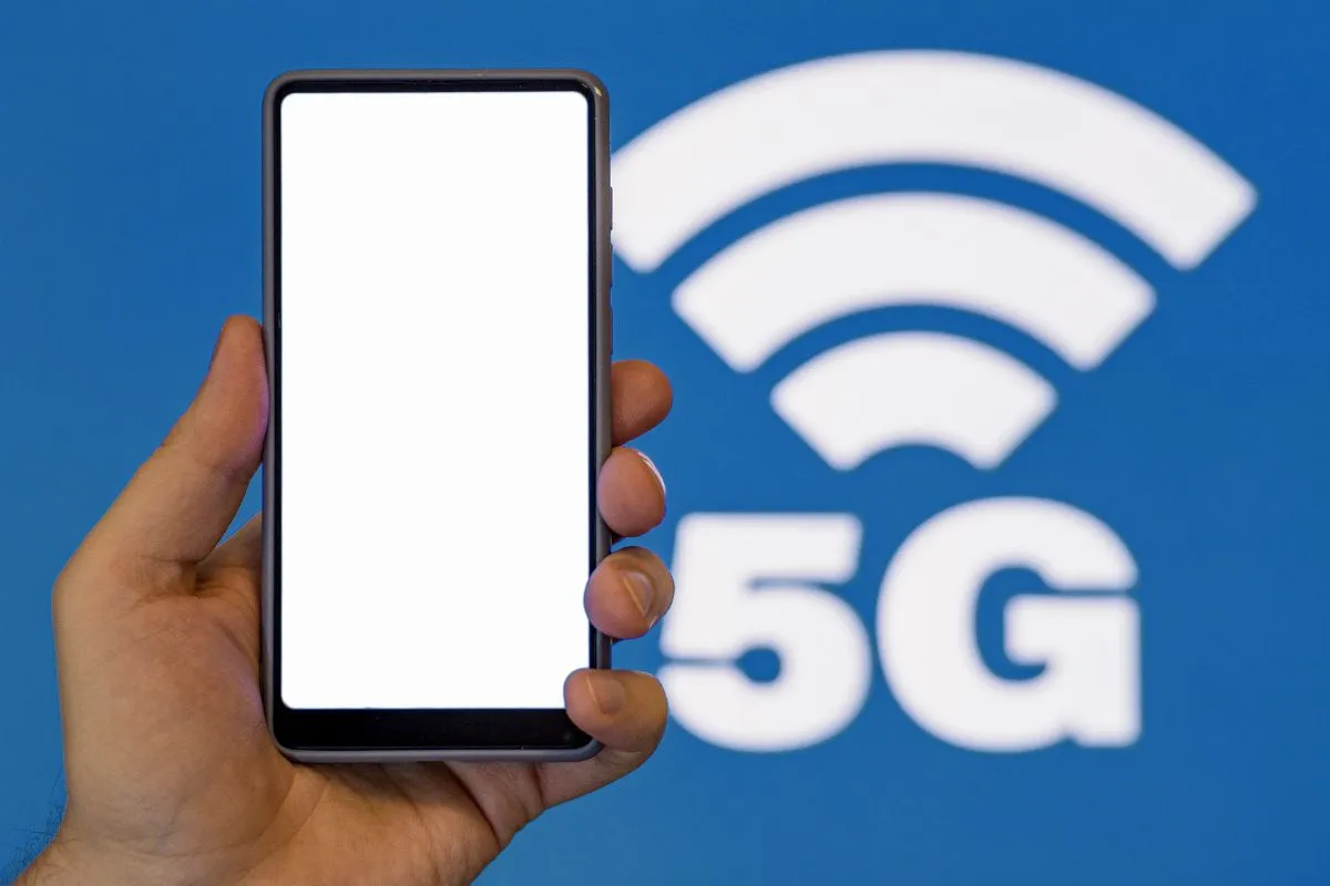 A person holding a smartphone in front of a 5G network sign