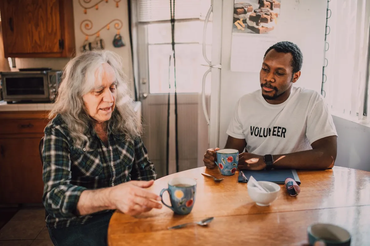 Volunteer tax preparer helping an older woman review her tax forms at a table