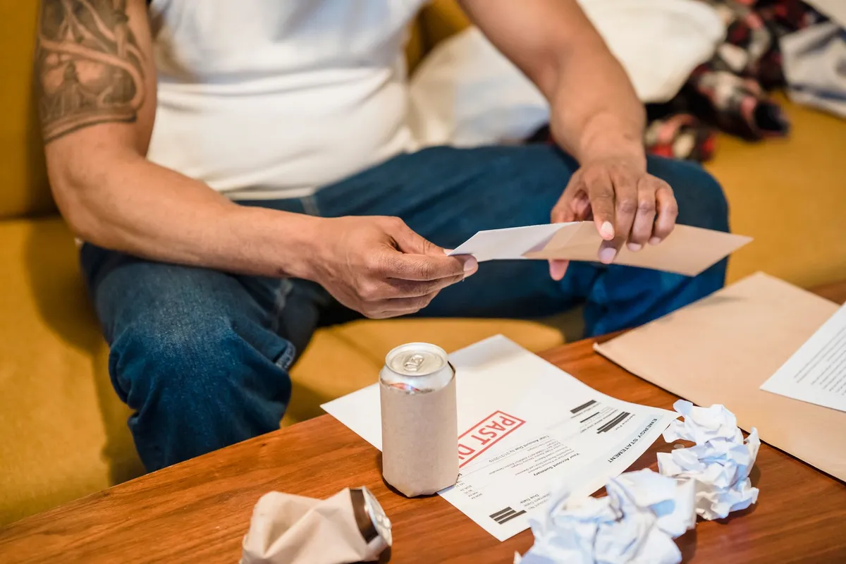 Older man sitting at a kitchen table sorting through mail and paperwork