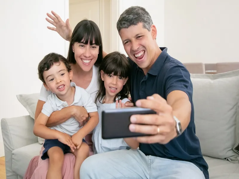 A family of four taking a selfie together on the couch