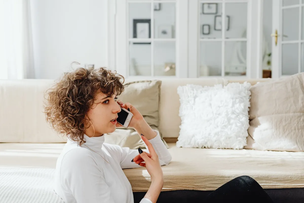 A woman making a phone call from her living room
