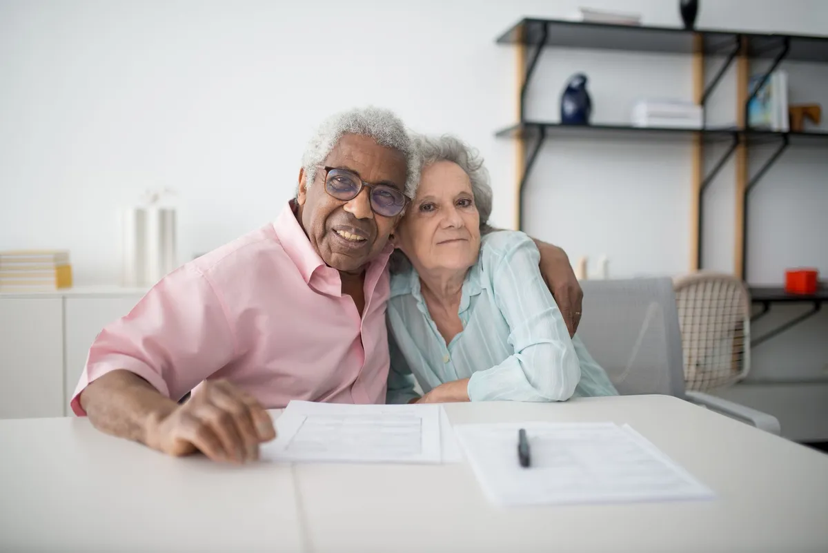 An older couple sitting together at a table with forms in front of them