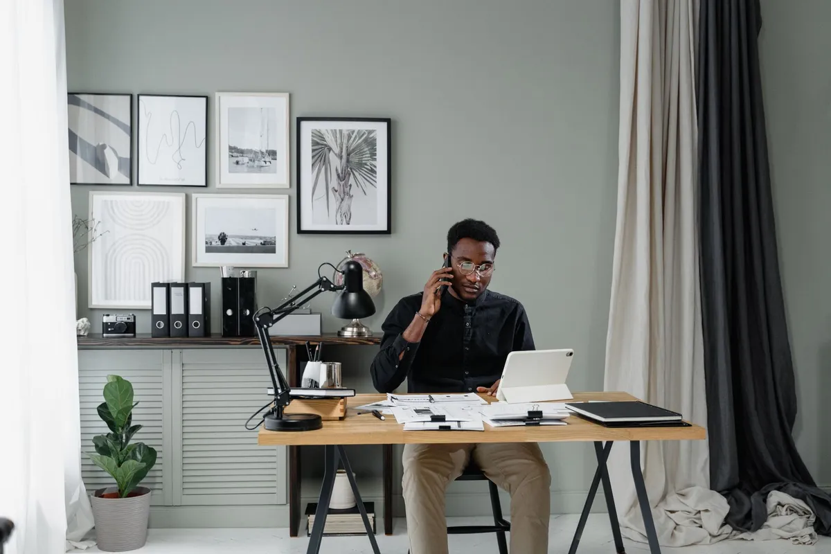 A man on a phone call at a desk covered with paperwork