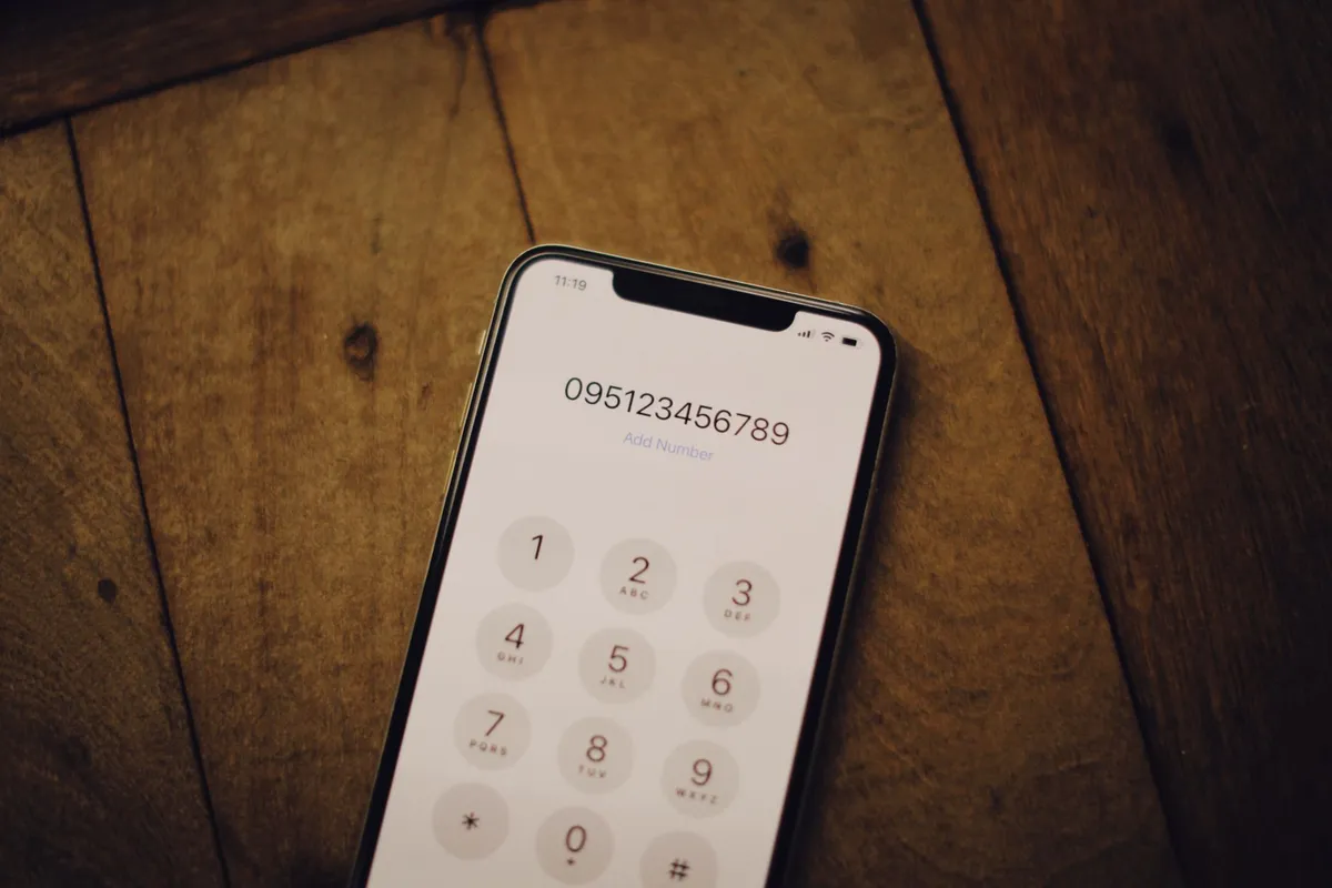 A close-up of a hand dialing a number on a smartphone keypad