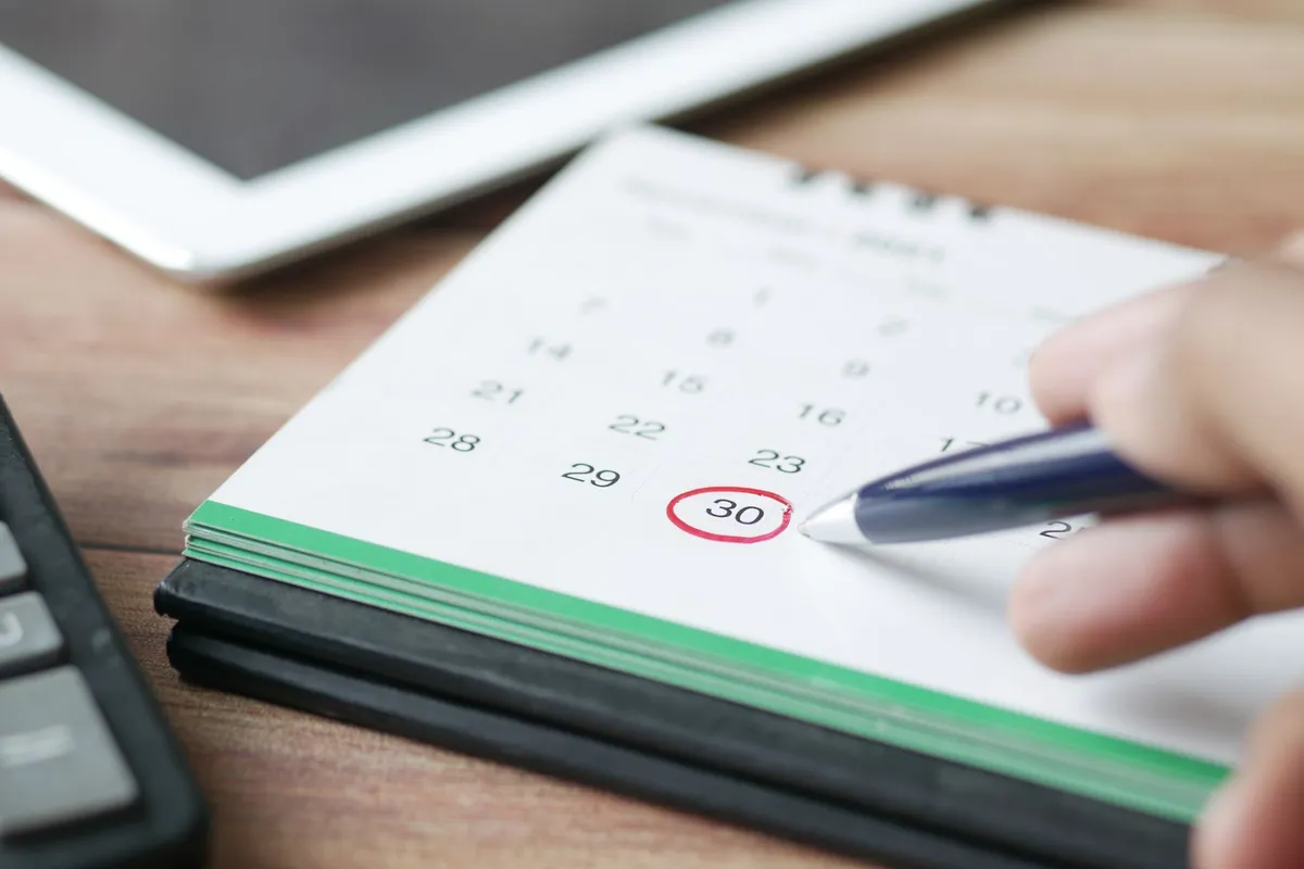 A calendar with a reminder circled next to a mobile phone on a desk