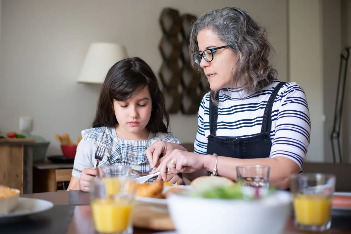 An adult daughter and her elderly mother sitting together at a kitchen table