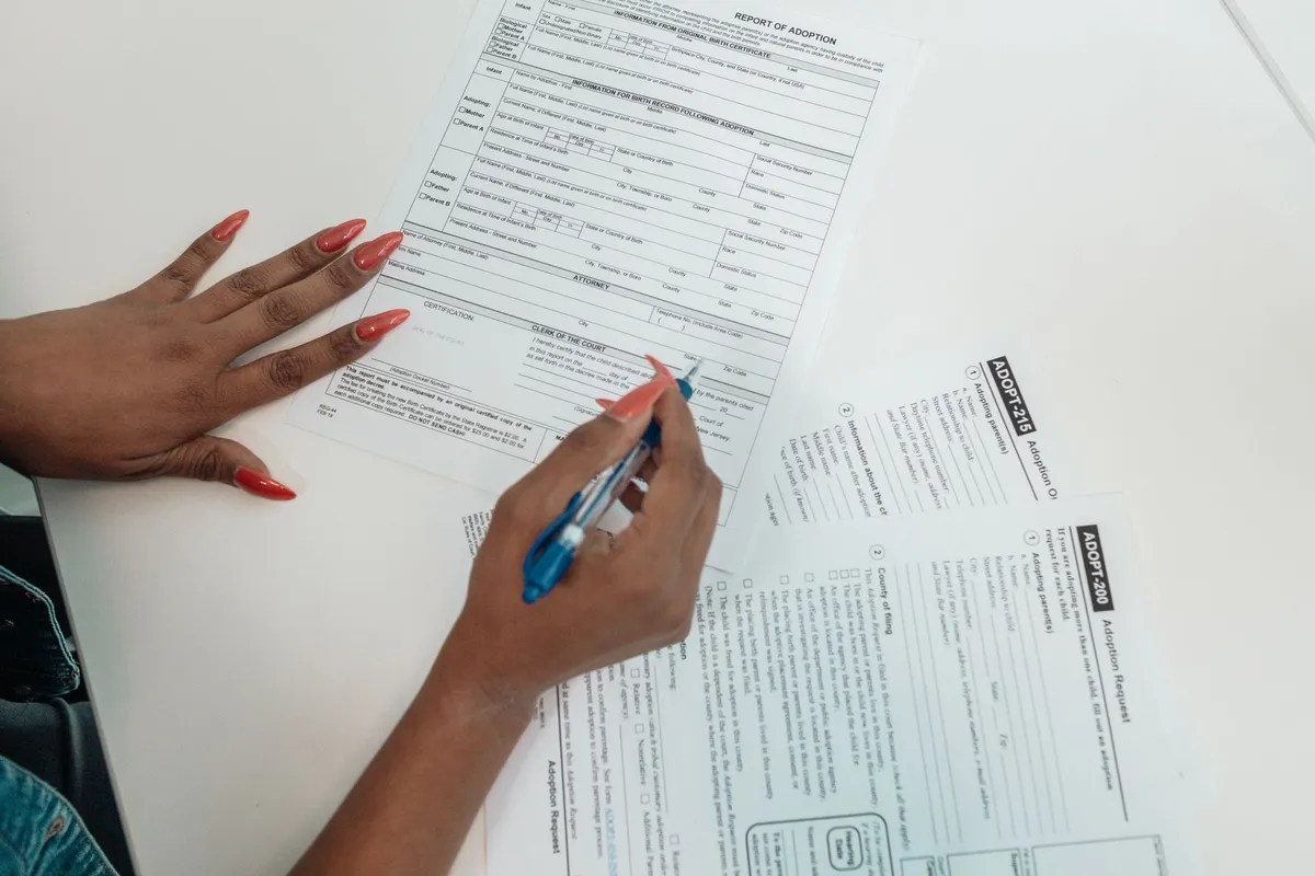 Person filling out a government benefits form with a black pen at a table