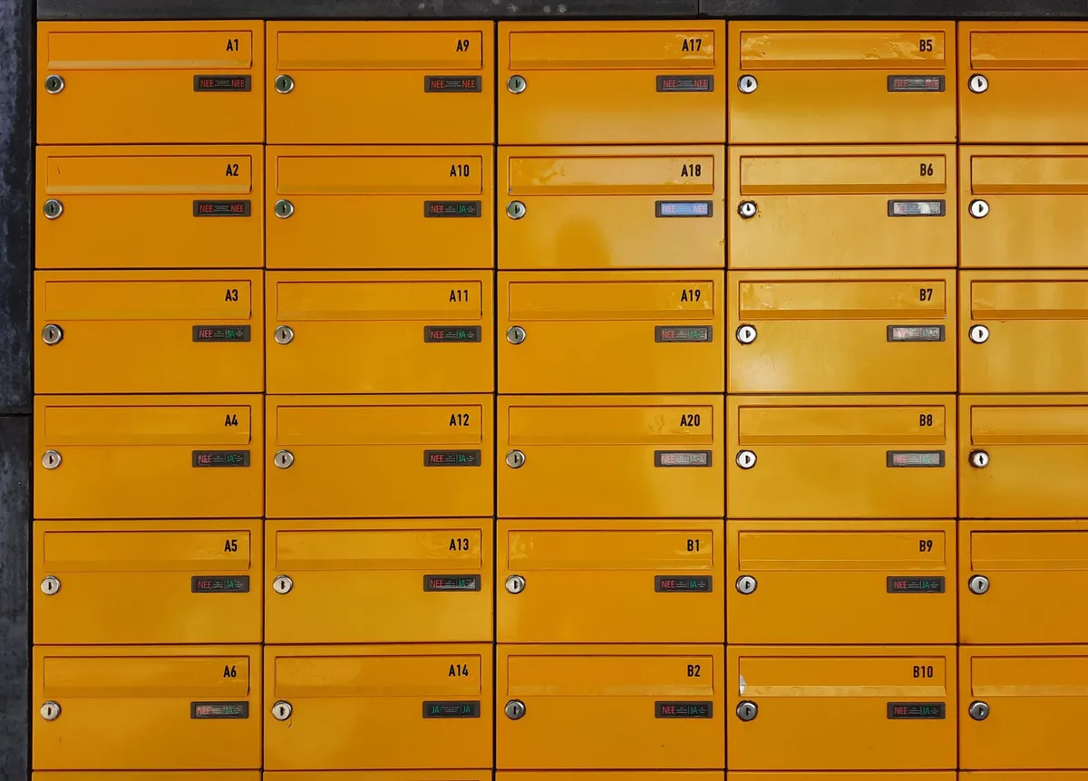 Row of mailboxes with unit numbers outside a small apartment building
