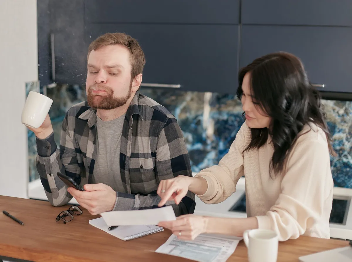 Household utility bills and a calculator spread across a kitchen table