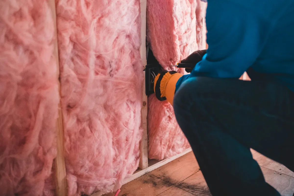 Contractor installing insulation batts in an attic