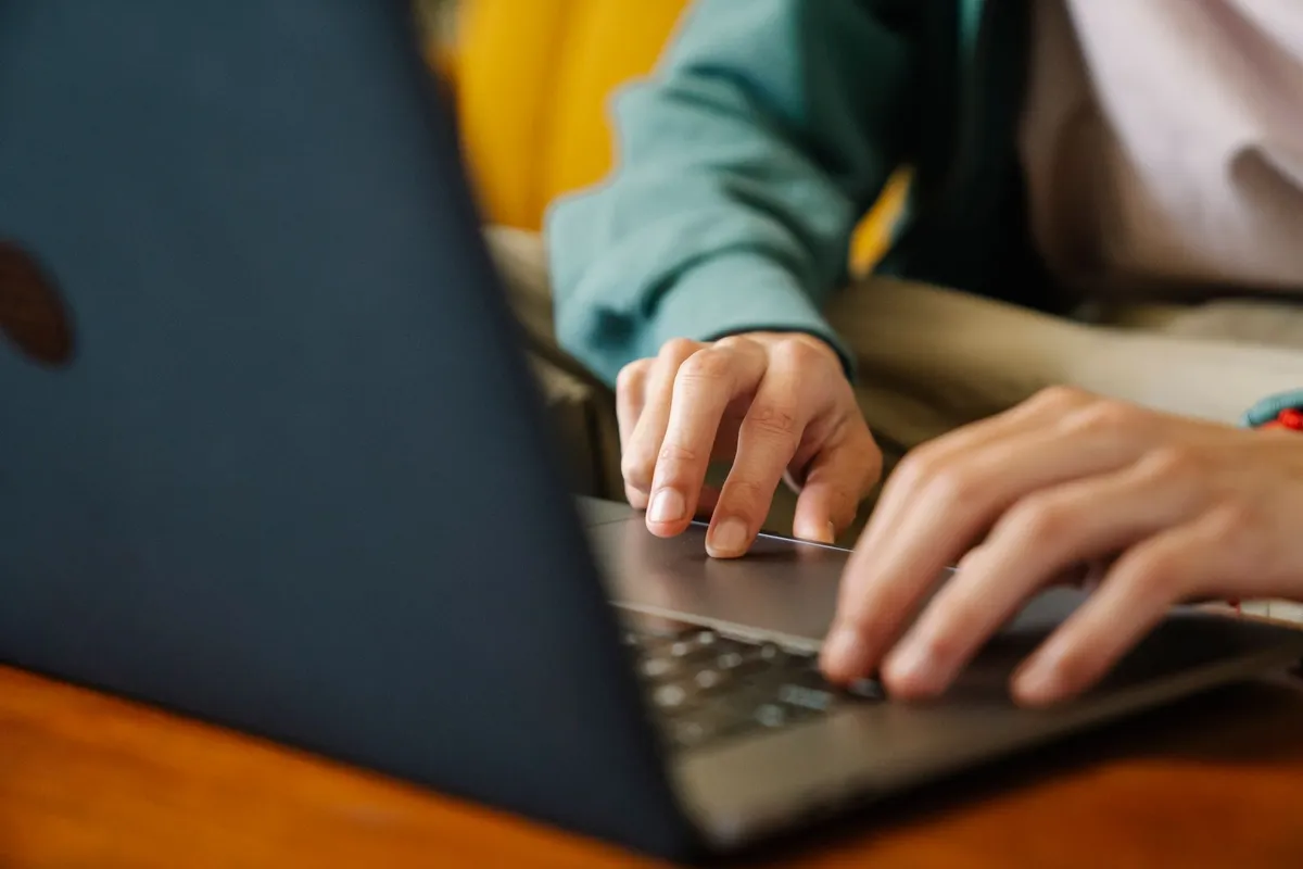Close-up of a person&rsquo;s hands typing on a laptop keyboard